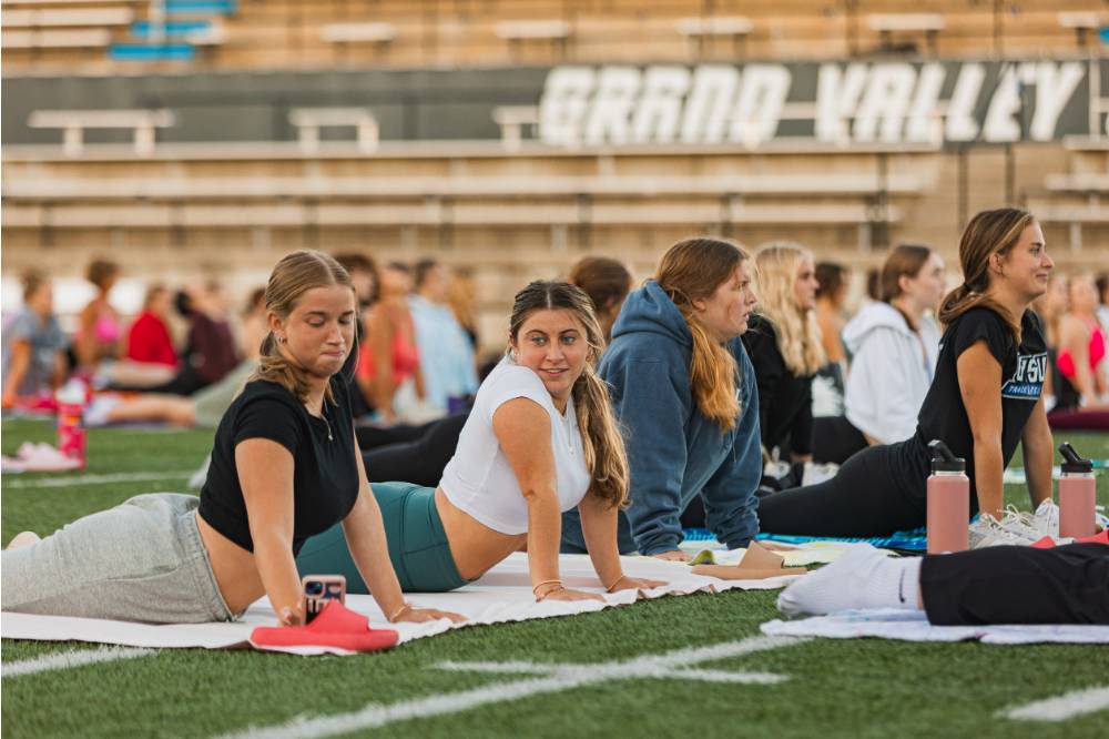 students doing the cobra yoga pose on the football field